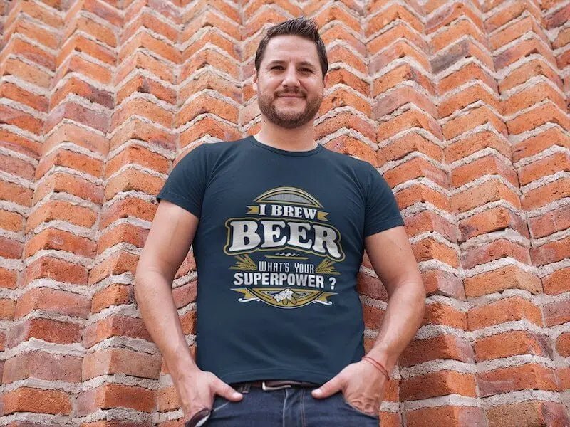 Ein Mann steht vor einer Backsteinmauer und trägt ein Hoppymerch „Ich braue Bier. Was ist deine Superkraft?“ Bio-T-Shirt.